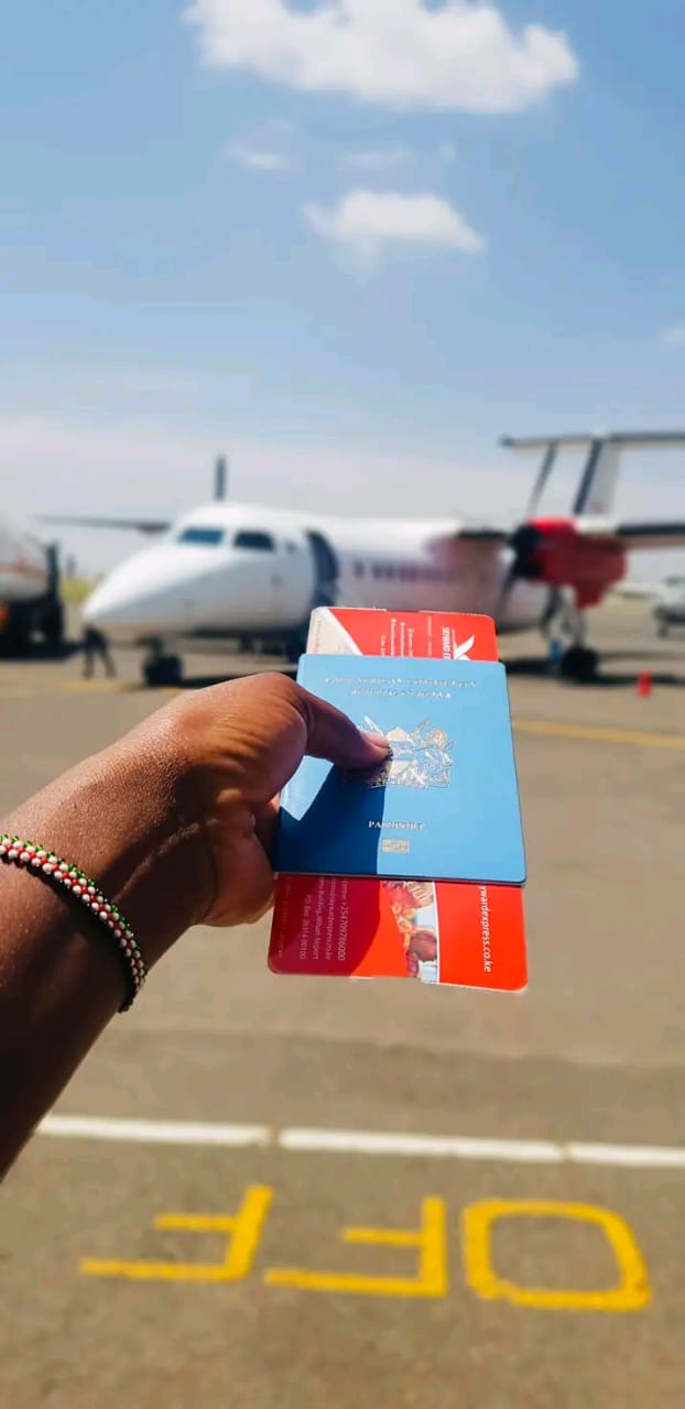 Traveller holding a passport and Skyward boarding passes with a Skyward aircraft behind on the tarmac