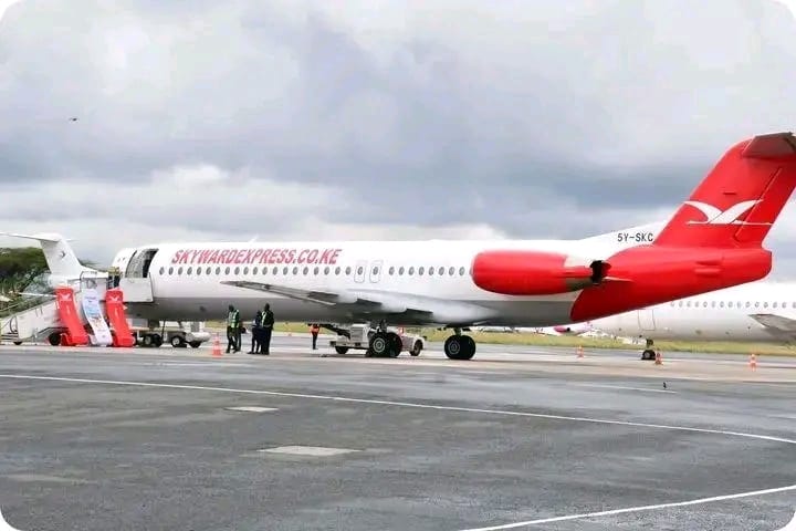 Skyward Express Fokker jet 5Y-SKC in red-and-white livery on the airport apron with boarding stairs
